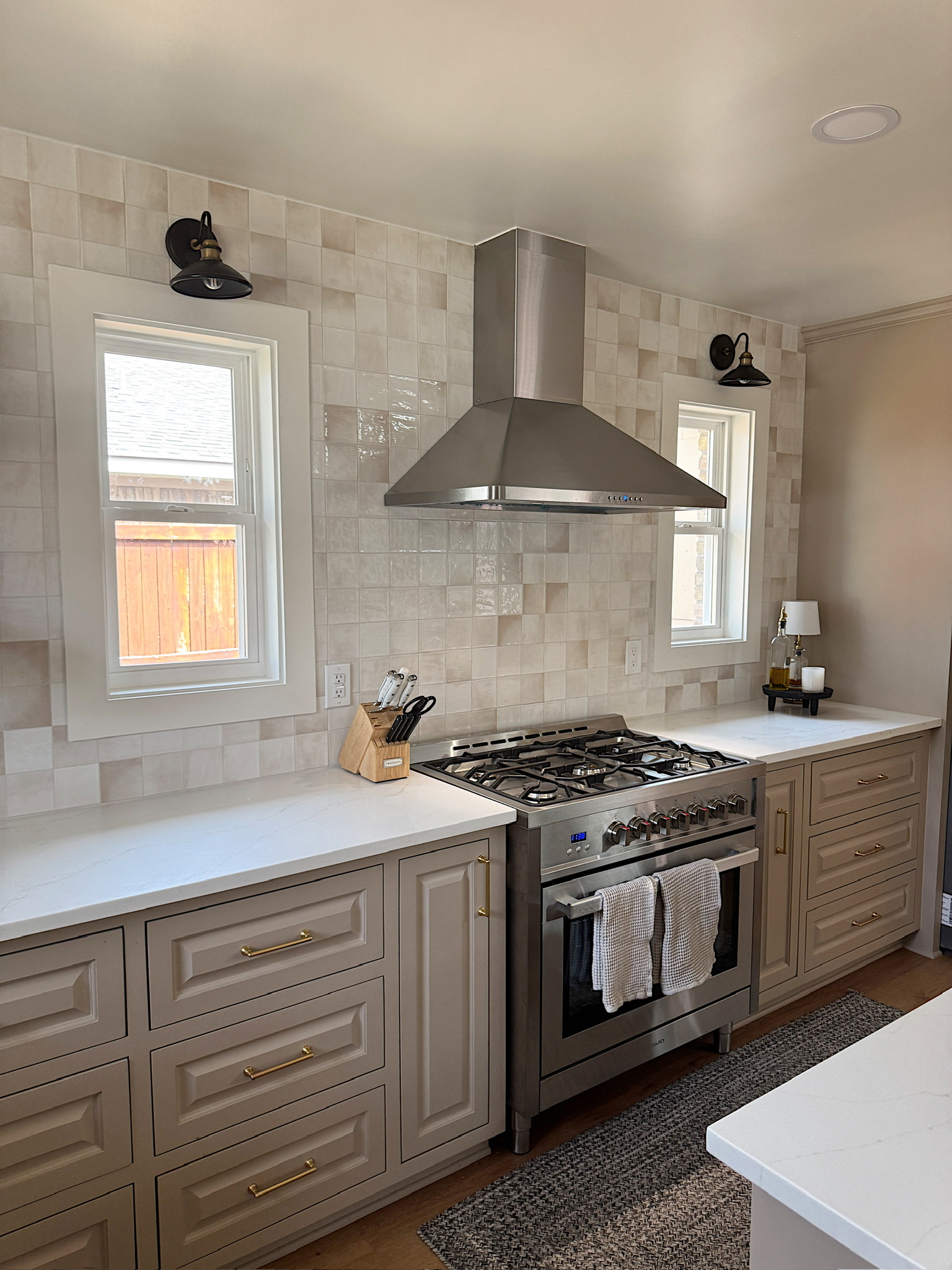 Completed kitchen renovation showing coordinated cabinetry, tile, windows, lighting, and ventilation